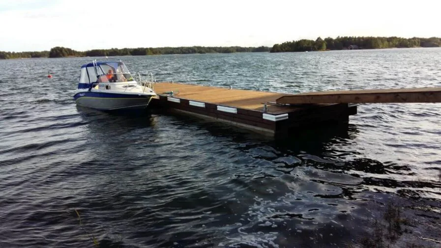 Ponttonilaituri ja vene kiinnitettynä laituriin mökkirannassa